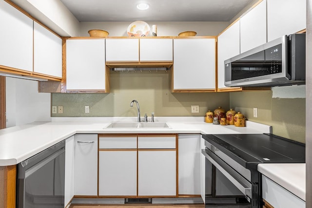 kitchen with white cabinetry, stainless steel appliances, light countertops, and a sink