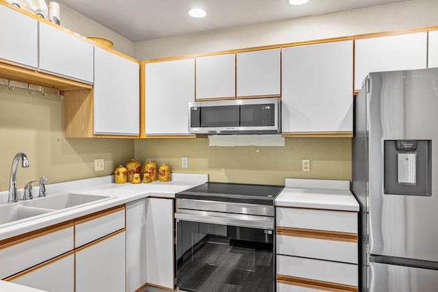 kitchen with appliances with stainless steel finishes, white cabinets, and a sink