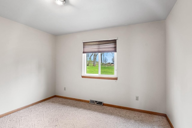 empty room featuring baseboards, visible vents, and light carpet