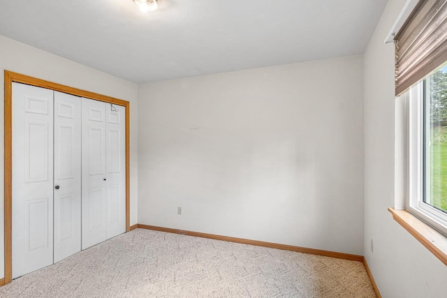 unfurnished bedroom featuring multiple windows, carpet floors, and baseboards