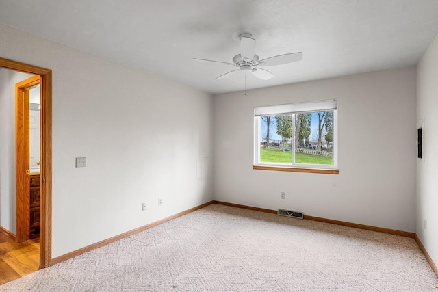 spare room featuring a ceiling fan, visible vents, light colored carpet, and baseboards