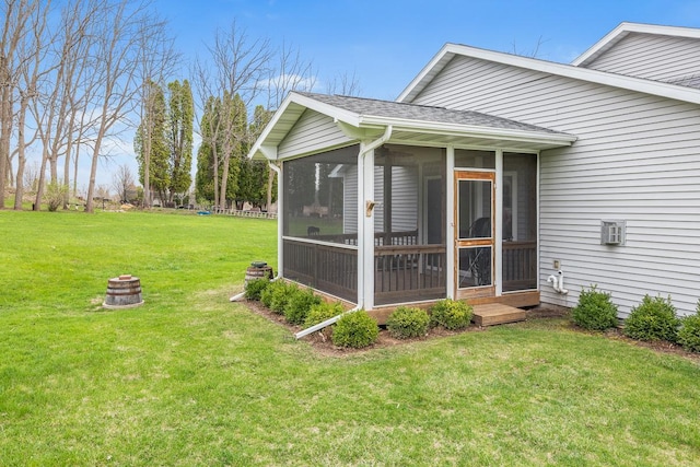 view of side of home with a sunroom, a yard, a shingled roof, and an outdoor fire pit