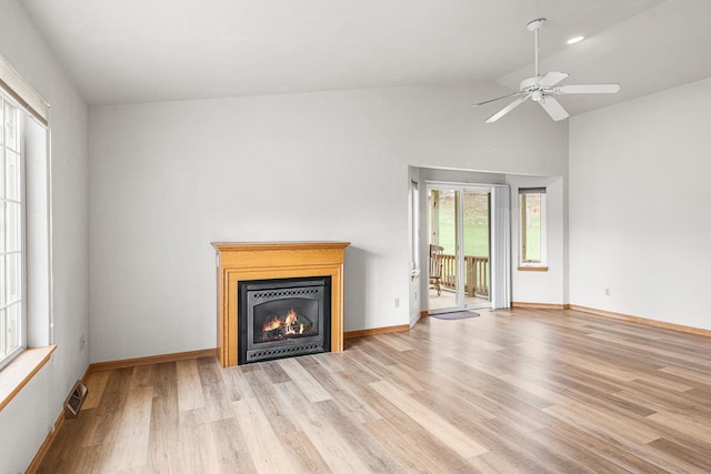 unfurnished living room with wood finished floors, a glass covered fireplace, baseboards, a ceiling fan, and lofted ceiling
