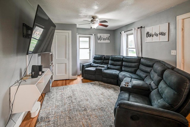 living room featuring a ceiling fan, a textured ceiling, wood finished floors, and a healthy amount of sunlight