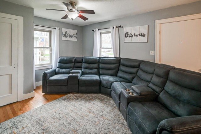 living room featuring a ceiling fan, baseboards, and light wood-type flooring