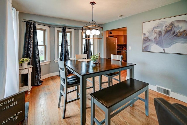 dining area featuring a notable chandelier, visible vents, baseboards, and light wood-style flooring