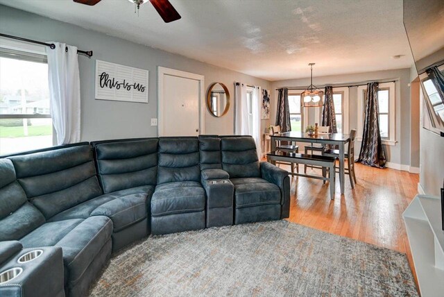 living room featuring a ceiling fan, baseboards, and wood finished floors
