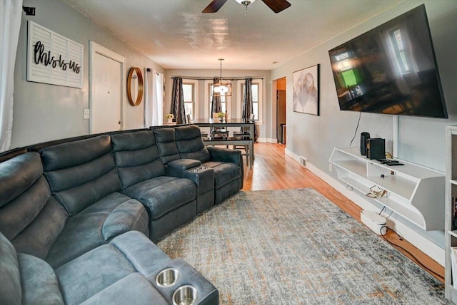 living room featuring baseboards, a ceiling fan, and wood finished floors