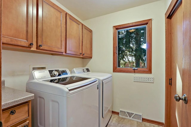 washroom with separate washer and dryer, visible vents, cabinet space, and baseboards