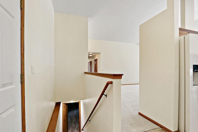 hall with an upstairs landing and carpet flooring