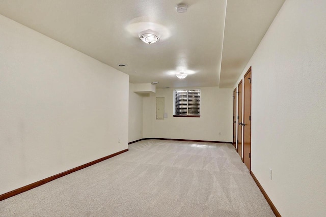 spare room featuring light colored carpet and baseboards