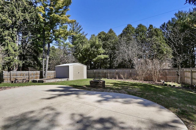 view of patio featuring a storage unit, a fenced backyard, and an outdoor fire pit