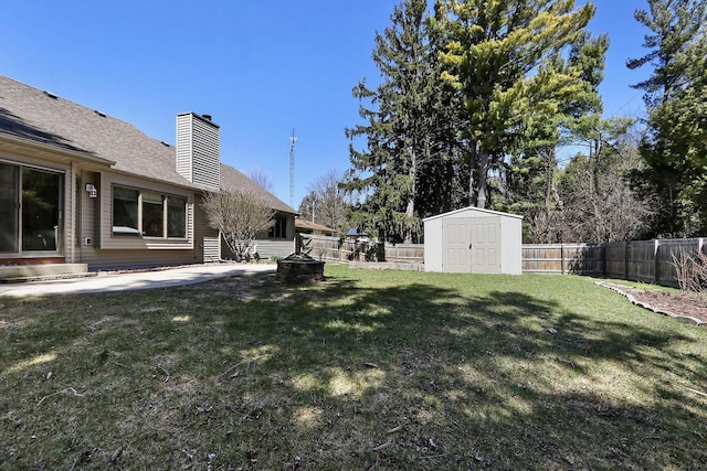 view of yard with a fire pit, a fenced backyard, an outbuilding, and a storage shed