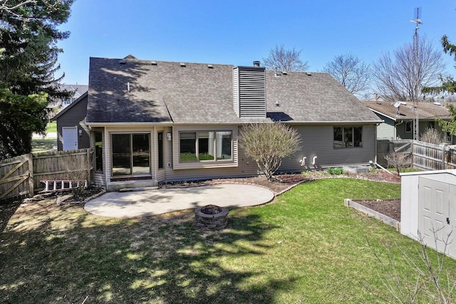 back of house featuring a fire pit, a patio, a chimney, a lawn, and a fenced backyard