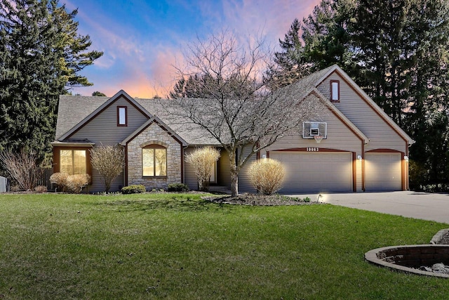 view of front of home with a front yard, a shingled roof, driveway, stone siding, and an attached garage
