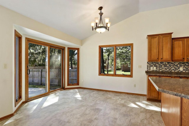 unfurnished dining area featuring baseboards, an inviting chandelier, and lofted ceiling