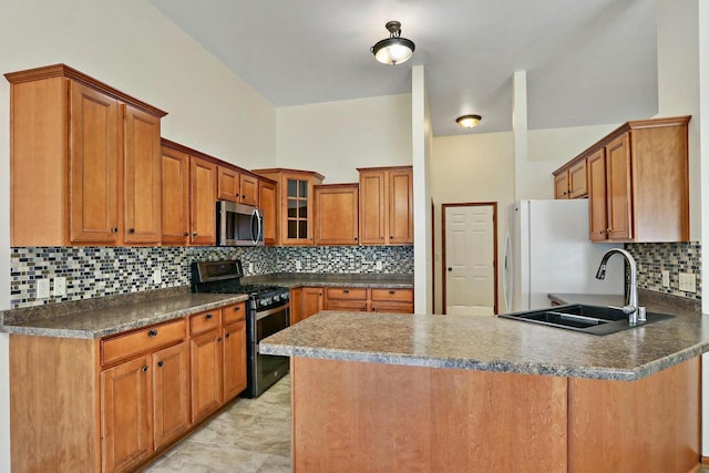 kitchen featuring a peninsula, a sink, appliances with stainless steel finishes, and brown cabinetry