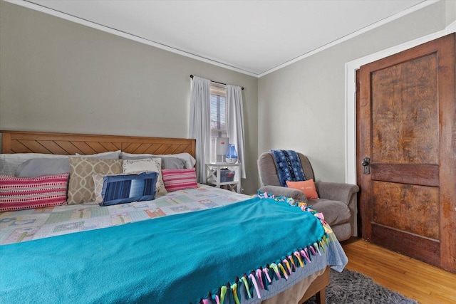 bedroom with wood finished floors and ornamental molding