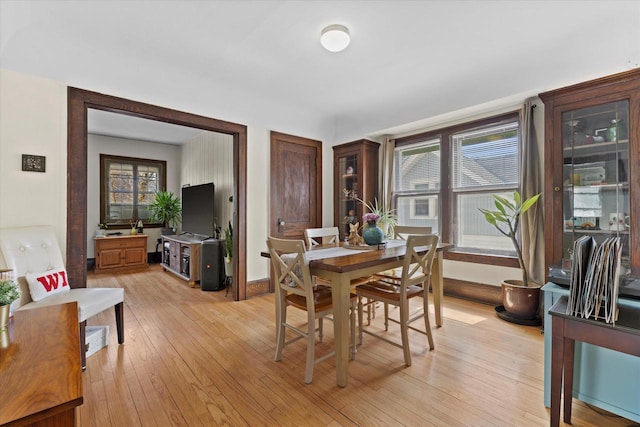 dining space with light wood-style flooring and baseboards