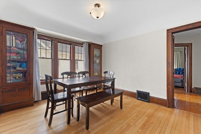 dining room with visible vents, light wood finished floors, and baseboards