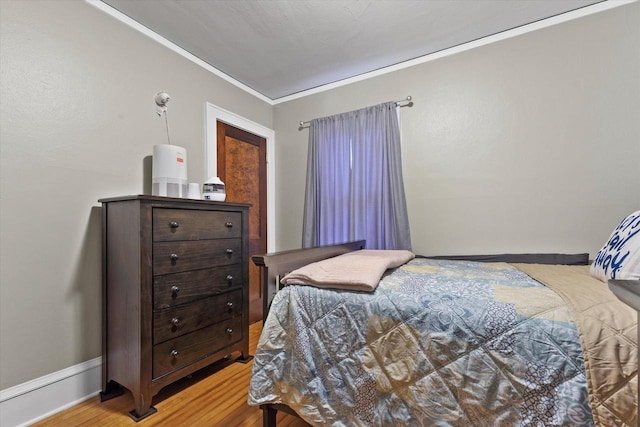 bedroom with crown molding and wood finished floors
