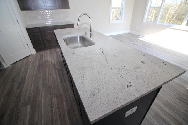 kitchen featuring dark wood-style floors, light stone countertops, backsplash, and a sink