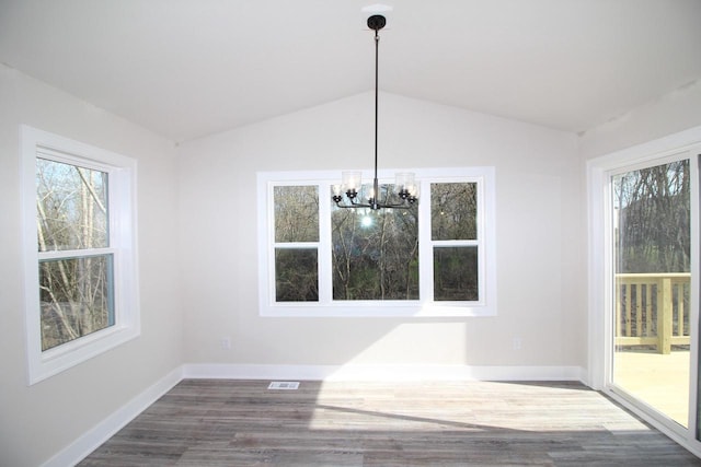 unfurnished dining area featuring a wealth of natural light, visible vents, a notable chandelier, and dark wood finished floors