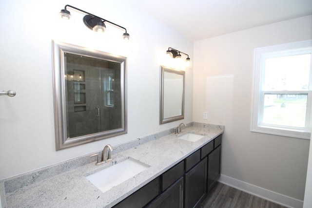 full bathroom featuring baseboards, wood finished floors, double vanity, and a sink