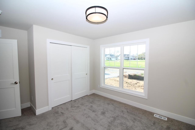 unfurnished bedroom featuring a closet, visible vents, carpet, and baseboards