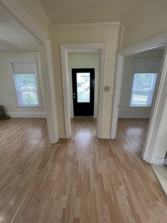 foyer entrance with crown molding, light wood-style flooring, and baseboards