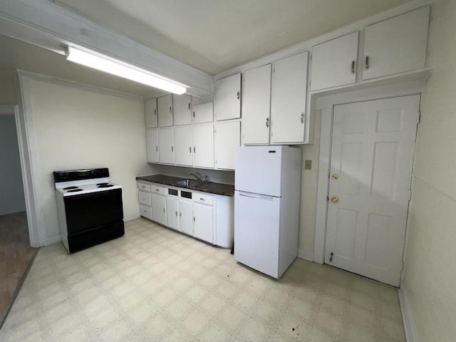 kitchen with a sink, dark countertops, freestanding refrigerator, electric stove, and light floors