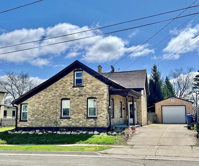 view of front of house featuring an outdoor structure, a detached garage, brick siding, concrete driveway, and fence