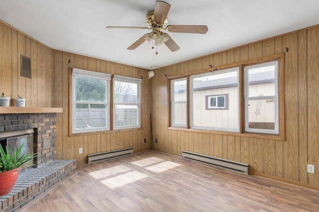 unfurnished living room featuring a fireplace, a baseboard radiator, wood finished floors, and a ceiling fan