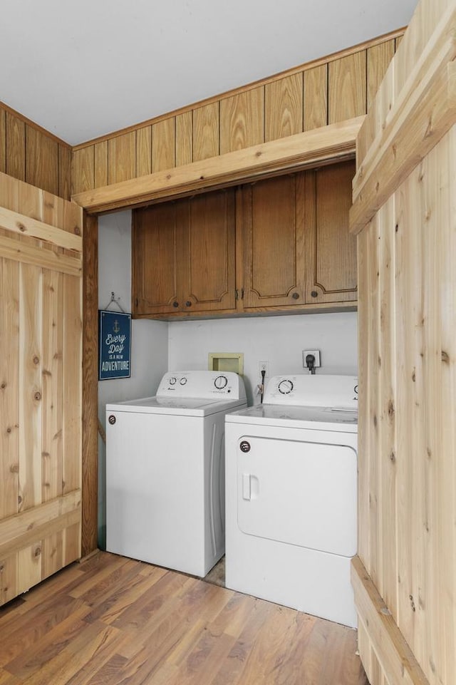washroom featuring washer and dryer, cabinet space, and light wood-style floors