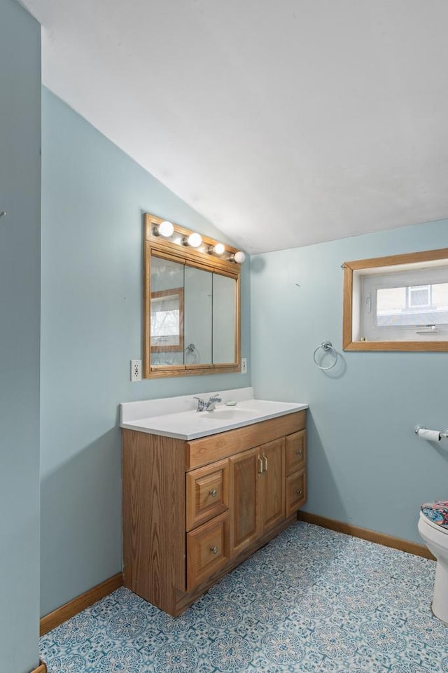 bathroom featuring baseboards, toilet, lofted ceiling, and vanity