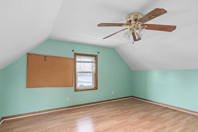 additional living space with light wood finished floors, a ceiling fan, vaulted ceiling, and baseboards