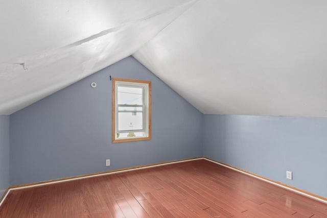 additional living space with wood finished floors, vaulted ceiling, and baseboards