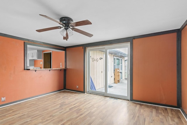 spare room with wood finished floors, ceiling fan, and baseboards