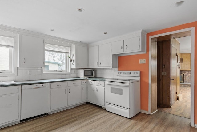 kitchen featuring white cabinetry, decorative backsplash, a sink, light wood-type flooring, and white appliances