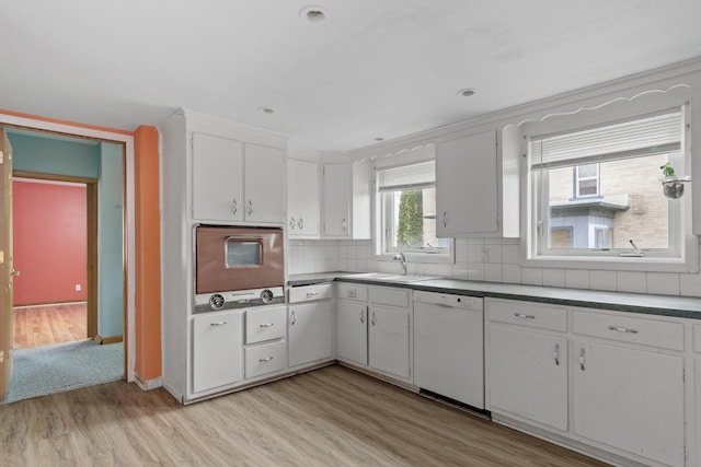 kitchen with a sink, light wood-style floors, wall oven, dishwasher, and white cabinets