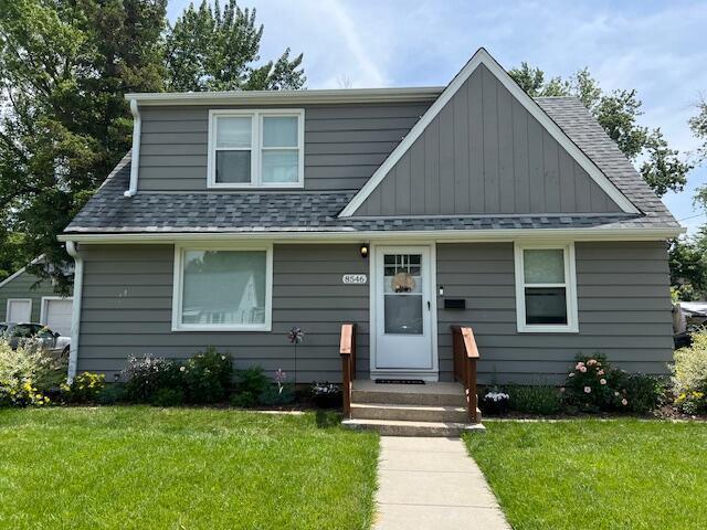 bungalow-style home featuring a shingled roof, board and batten siding, and a front lawn