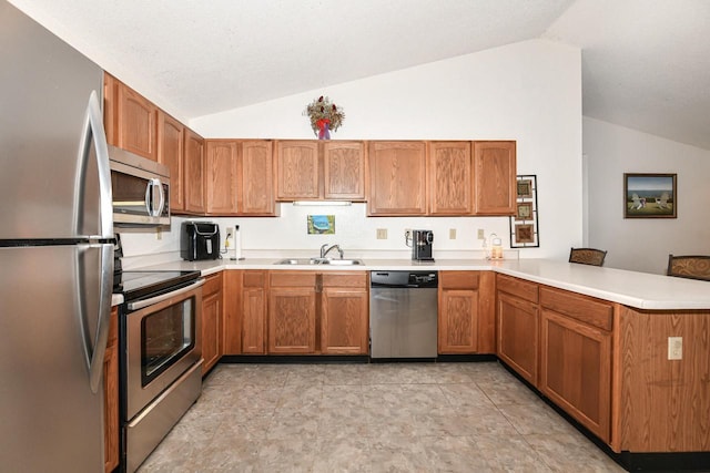 kitchen with a peninsula, stainless steel appliances, vaulted ceiling, and a sink