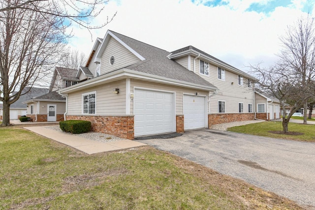 view of side of home with brick siding, aphalt driveway, a shingled roof, a garage, and a lawn