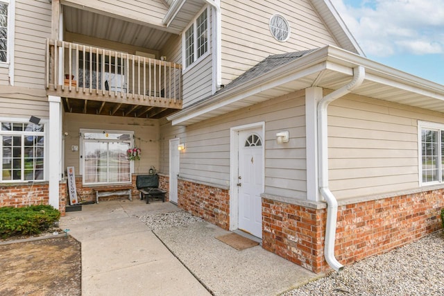 property entrance with brick siding and a balcony