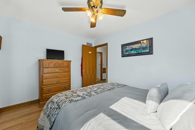 bedroom featuring a ceiling fan, visible vents, wood finished floors, and baseboards