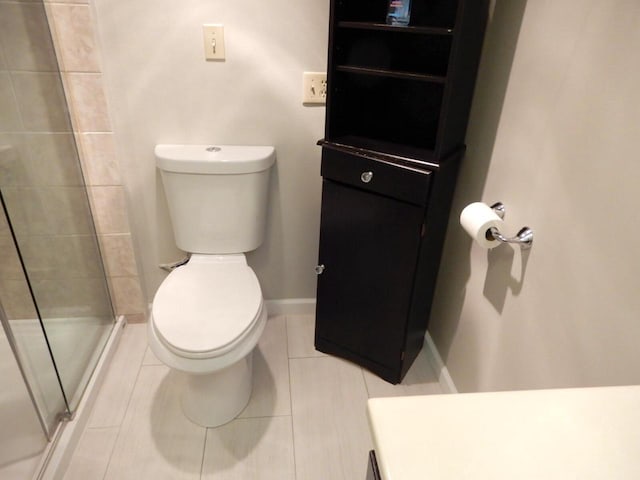 full bath featuring tile patterned floors, baseboards, a stall shower, and toilet