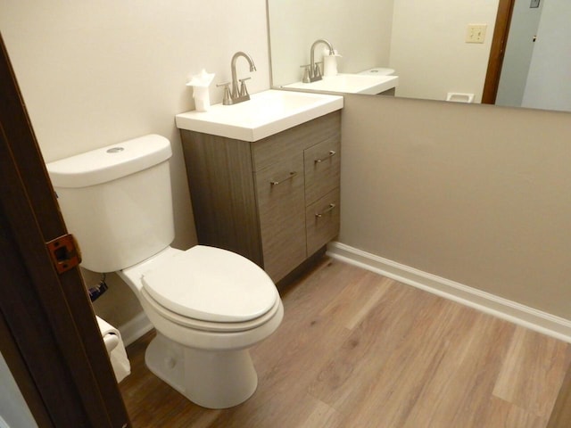 bathroom featuring toilet, vanity, and wood finished floors