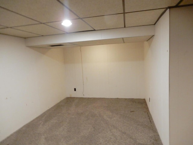 finished below grade area featuring a paneled ceiling and carpet flooring
