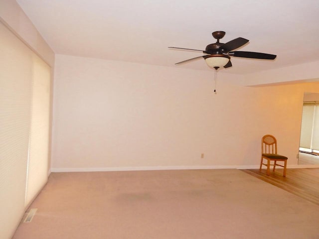 unfurnished room featuring a ceiling fan, baseboards, and light carpet