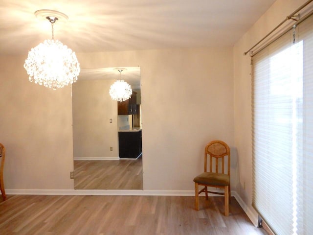 sitting room featuring wood finished floors, a chandelier, and baseboards